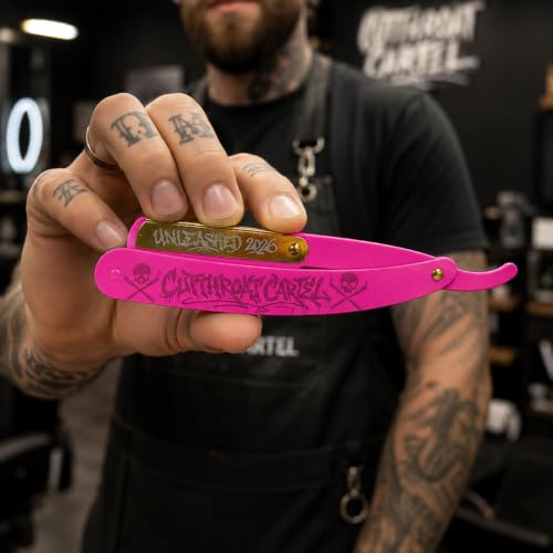 A barber with tattooed hands holding the open pink razor in a barbershop, Cutthroat Cartel lettering on the wall behind.